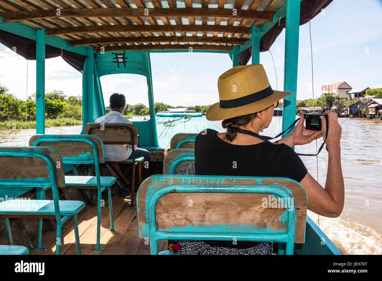 Une femme prend une photo de KOMPONG PHLUK, un village flottant, à partir d'un bateau comme elle tours sur une rivière ; la province de Siem Reap, Cambodge Banque D'Images