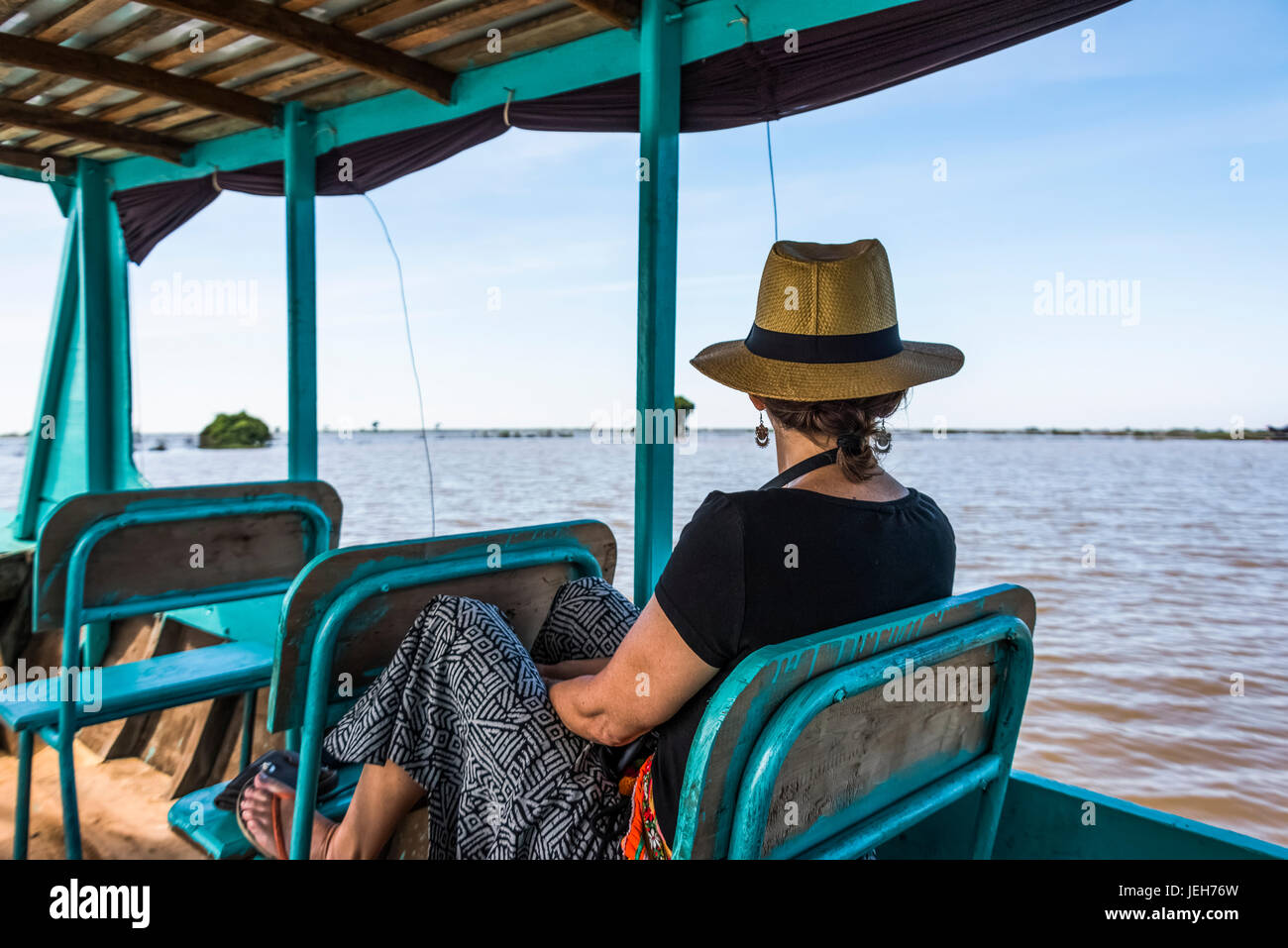 Une femme assise sur un bateau en voyant l'eau comme il tours sur une rivière ; la province de Siem Reap, Cambodge Banque D'Images