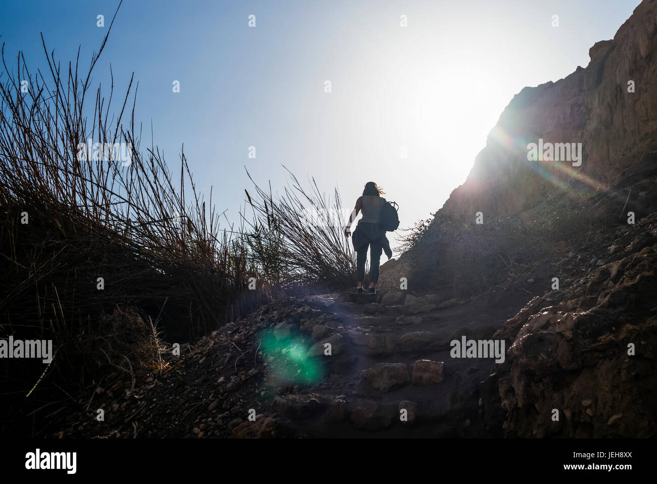 Une jeune femme robuste randonnées, marches de pierre à Ein Gedi, avec la lumière du soleil illumine le ciel, au sud du district, Israël Banque D'Images