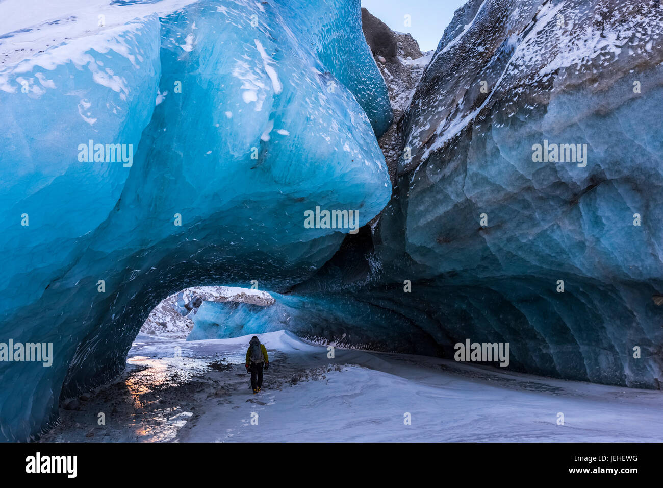 Un homme marche sous une grande formation de l'arche de glace détachés de l'organe principal de Black Rapids Glacier en hiver, l'intérieur de l'Alaska, USA Banque D'Images