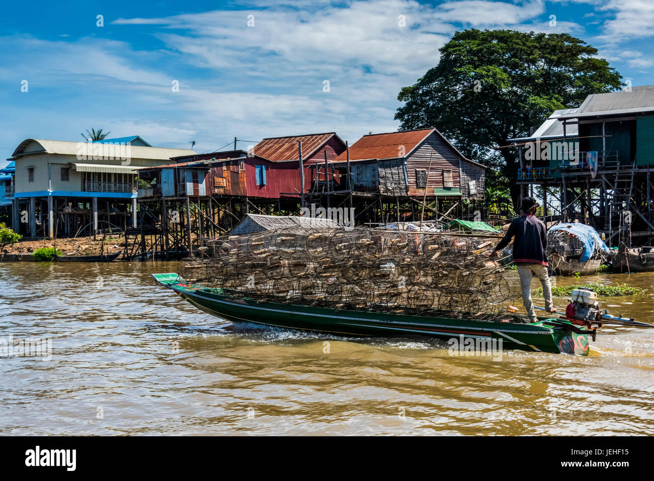 Un homme transportant des marchandises dans un bateau sur une rivière par un village flottant appelé Kampong Phluk ; la province de Siem Reap, Cambodge Banque D'Images