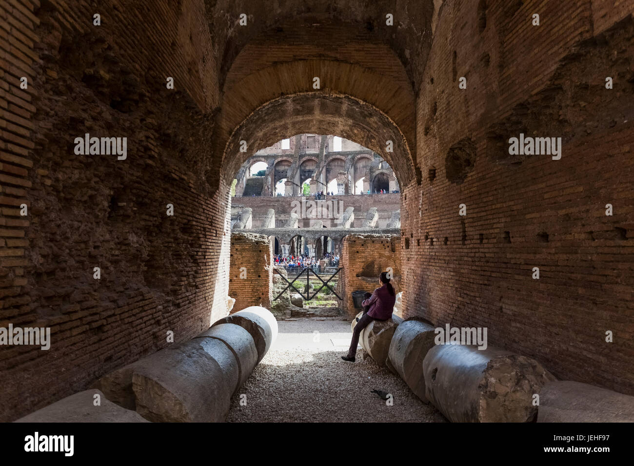 Un touriste est assis sur une colonne brisée, tombés à l'intérieur du Colisée, Rome, Italie Banque D'Images