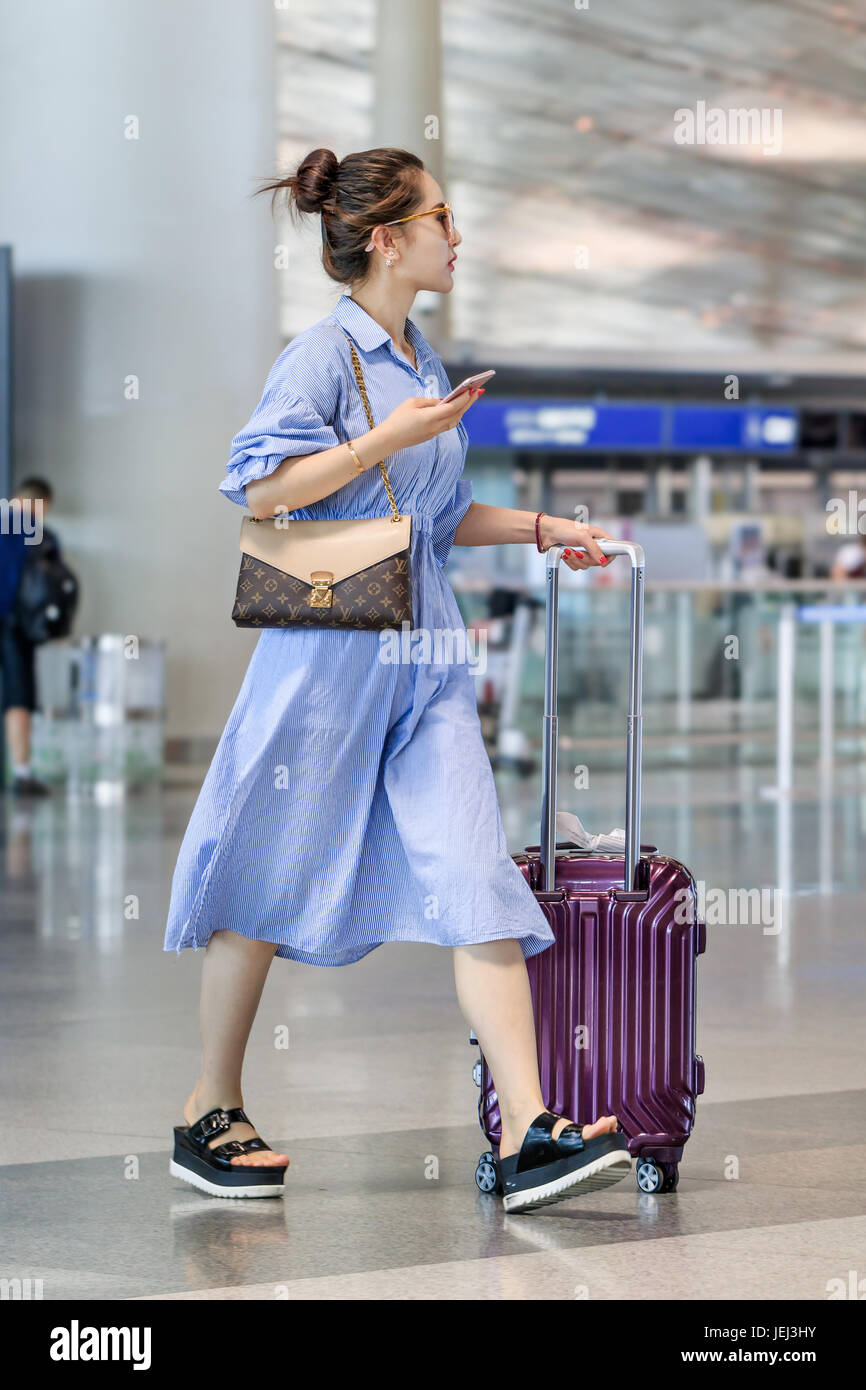 PÉKIN-13 JUILLET 2016. Jeune fille à la mode avec des promenades en valise à l'aéroport international de Beijing Capital, terminal 3. Banque D'Images