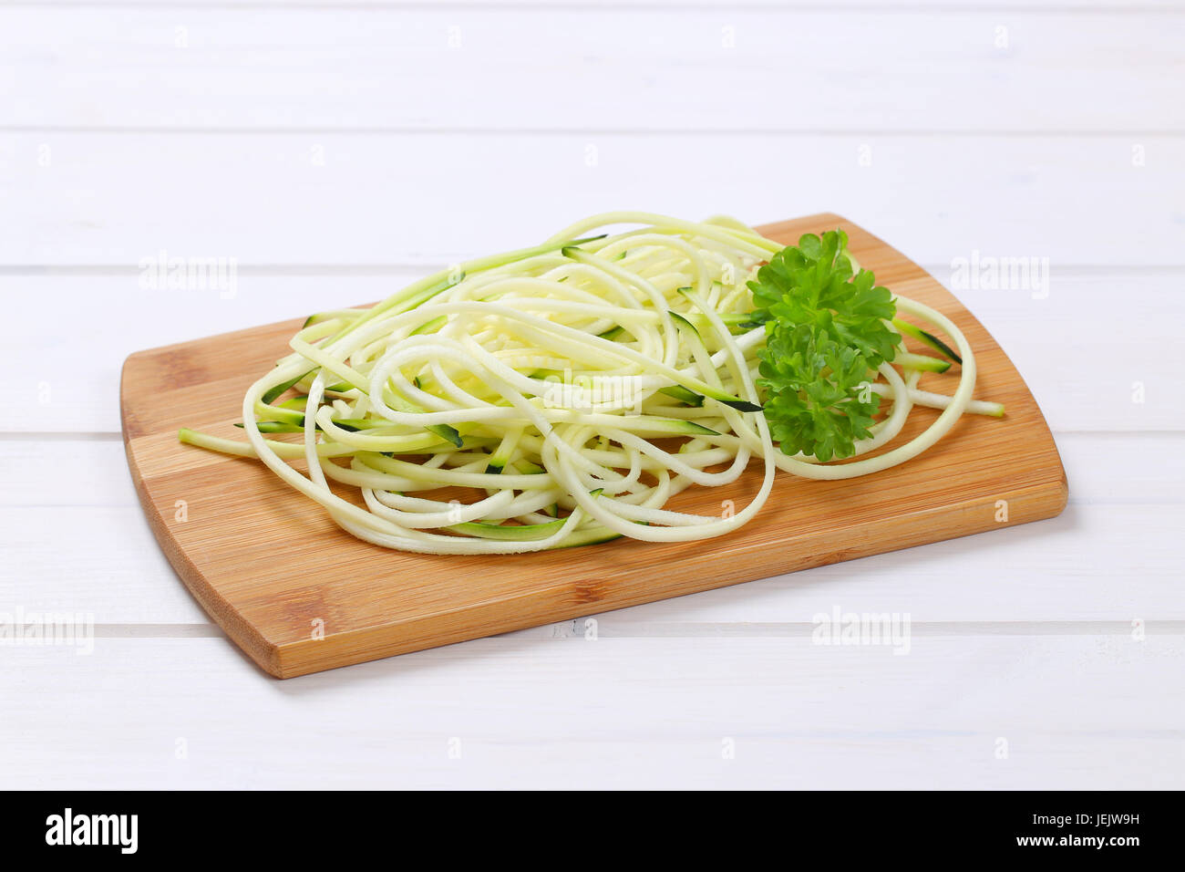 Tas de nouilles de courgettes crus sur planche à découper en bois Banque D'Images