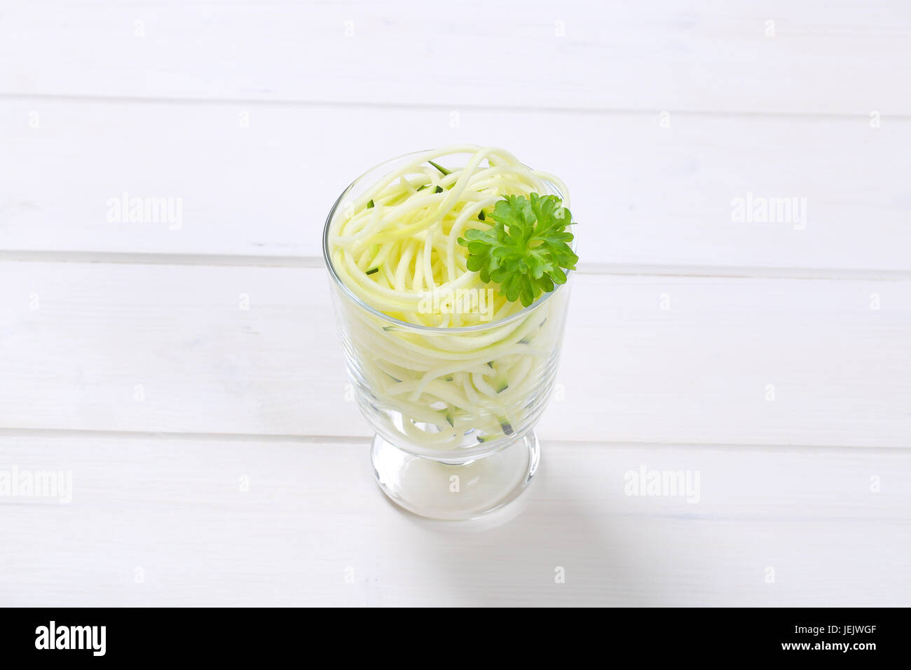 Verre de courgette crue sur fond de bois blanc nouilles Banque D'Images