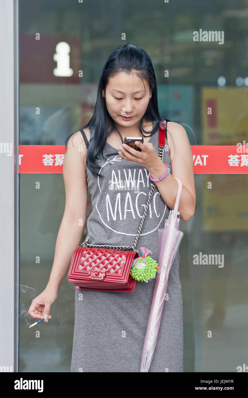 PÉKIN-18 JUILLET 2015. Une femme fume la cigarette à l'extérieur du centre commercial Livat. Le tabagisme public dans la capitale chinoise est désormais interdit. Banque D'Images