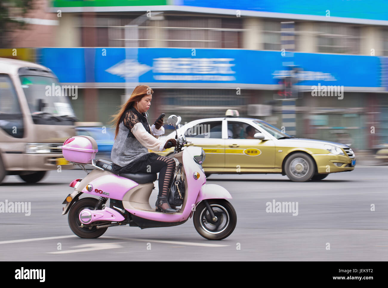 NANJING-LE 25 MAI 2014. Femme sur e-bike occupée avec smartphone. La Chine compte environ 500 millions d'utilisateurs de smartphones et le nombre augmente. Banque D'Images