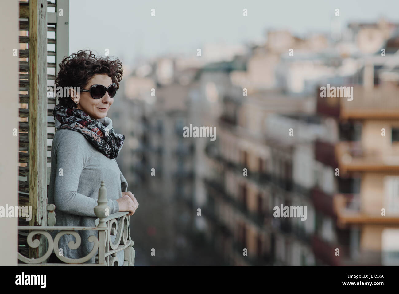 Femme souriante sur un balcon avec vue sur la ville, Barcelone, Catalogne, Espagne Banque D'Images