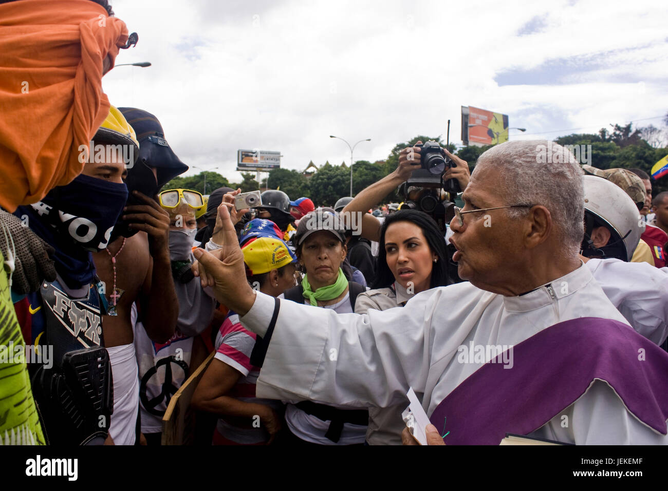 Un prêtre parle et bénir un groupe de manifestants à l'extérieur d'une base aérienne militaire au cours d'une manifestation contre le président Maduro. Banque D'Images