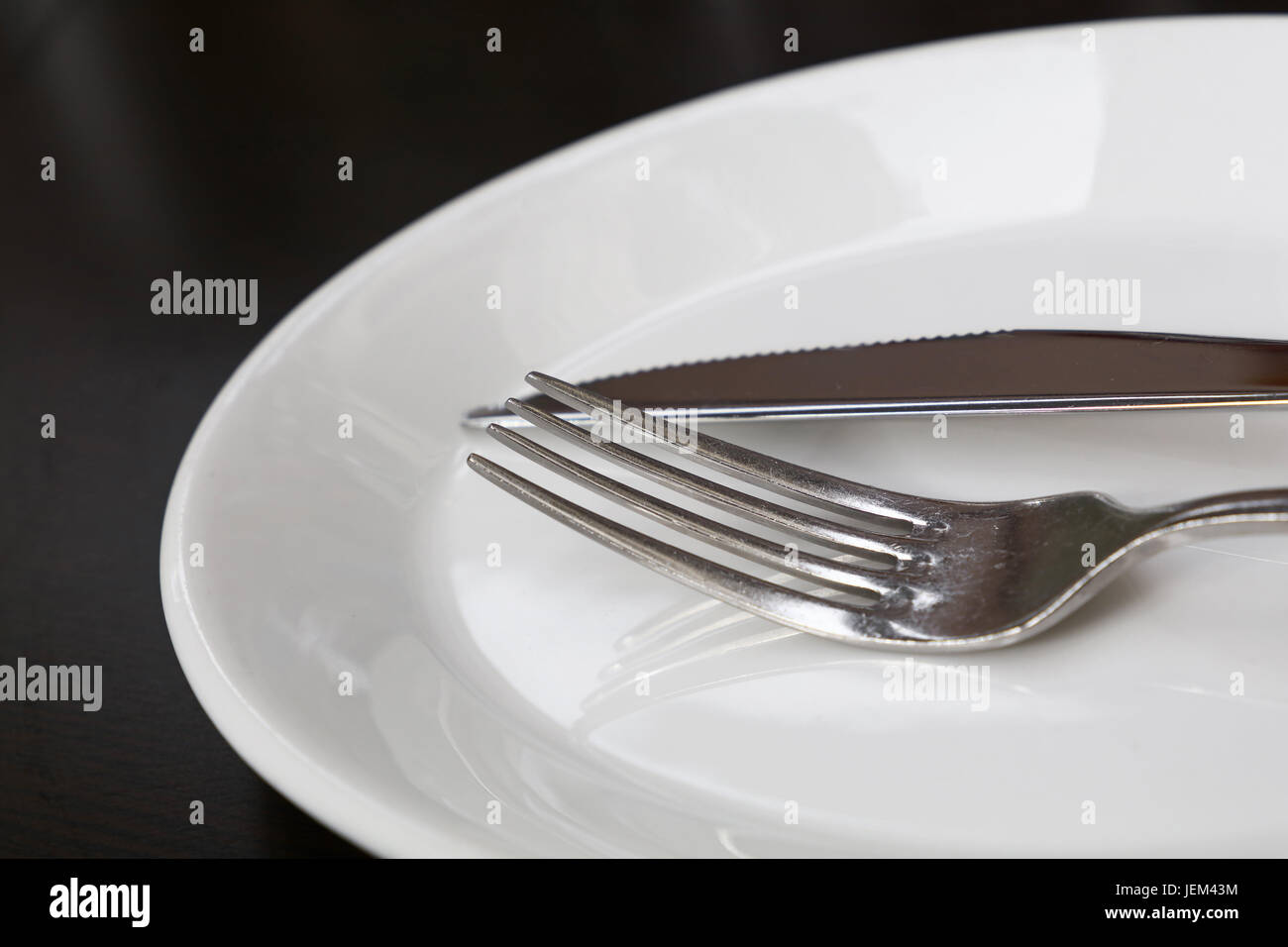 Metal fourchette et couteau de table blanc sur plaque porcelaine ustensiles de table noire, Close up, low angle view Banque D'Images