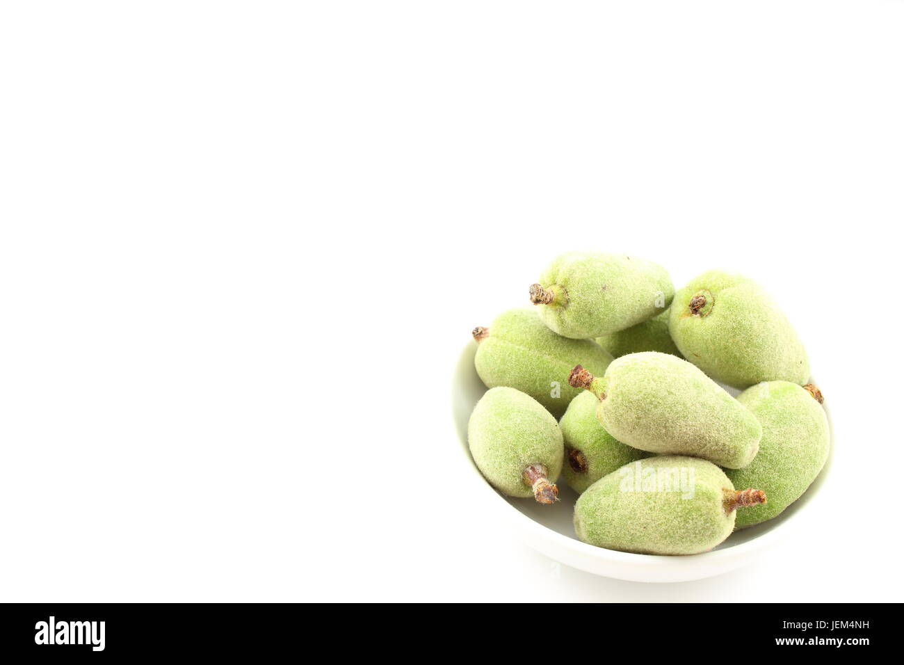 Composition de fruits amande verte fraîche dans un petit bol blanc Banque D'Images