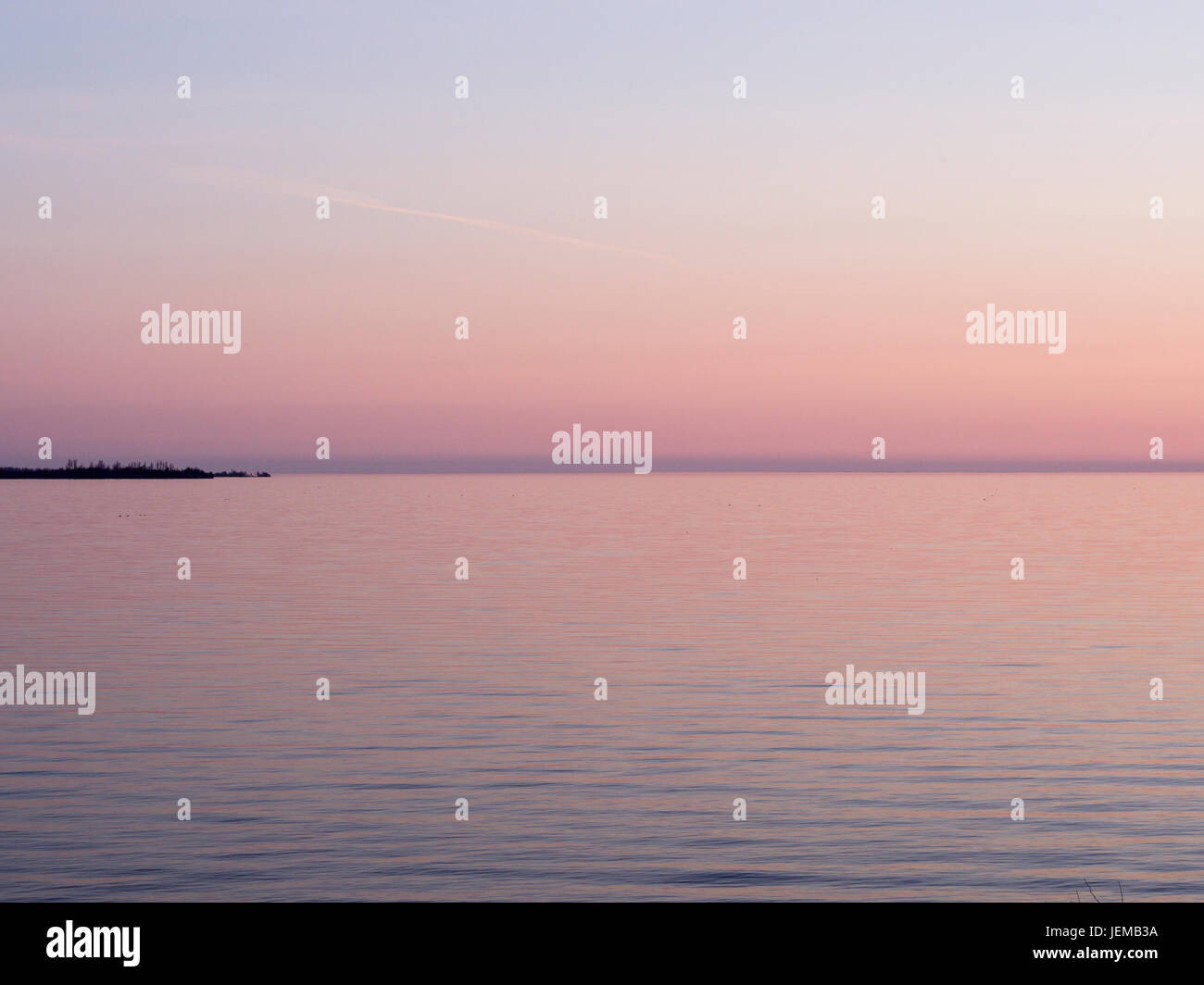 Sunset Glow sur le lac Ontario : Un ciel rose s'allume les eaux du lac Ontario à l'ouest de Kingston. La pointe de l'île Wolfe est à l'horizon. Banque D'Images