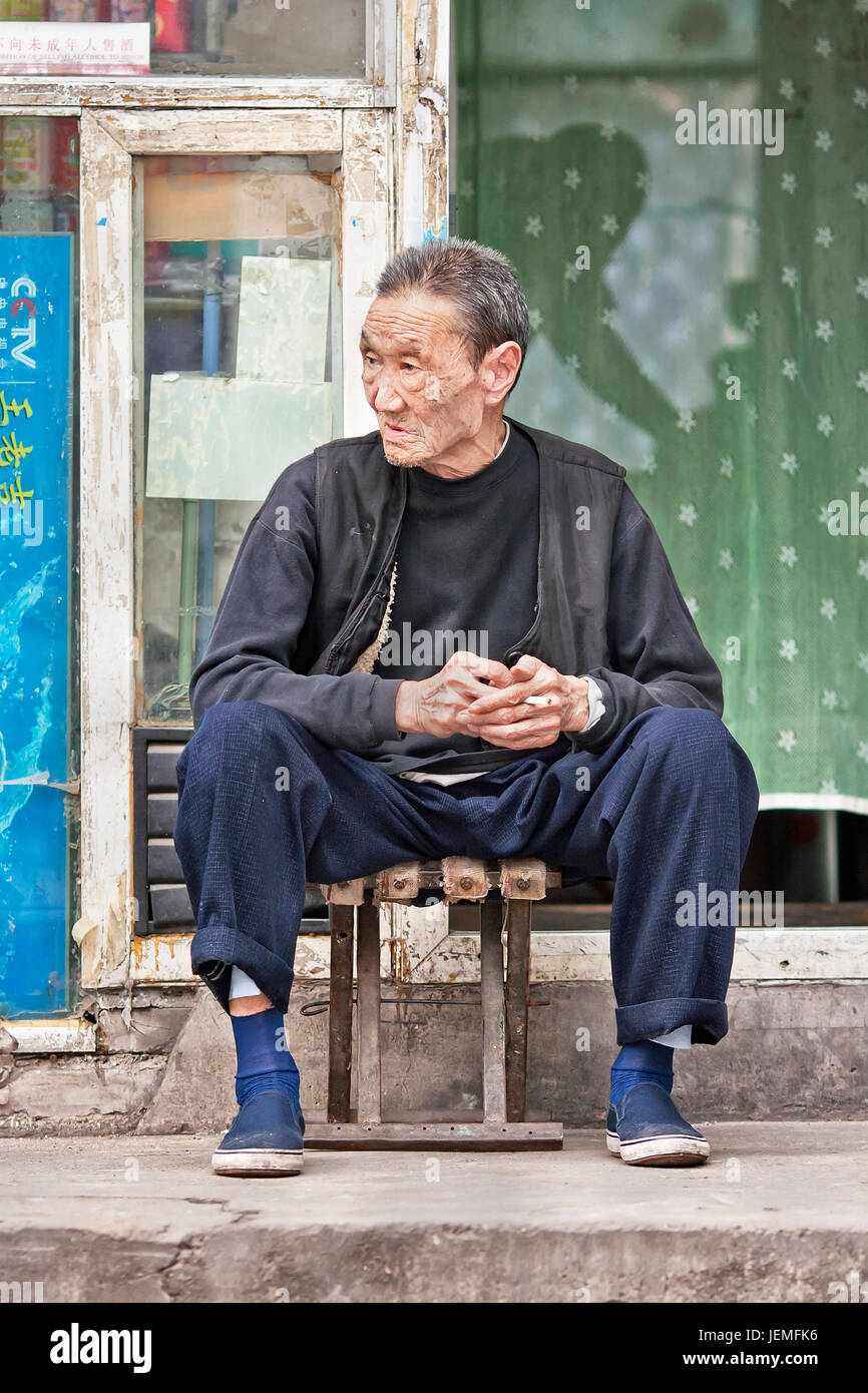 BEIJING-SEPT. 28. Chinois ancien homme est assis en face de sa maison, situé dans un hutong dans le centre-ville de Beijing. Banque D'Images