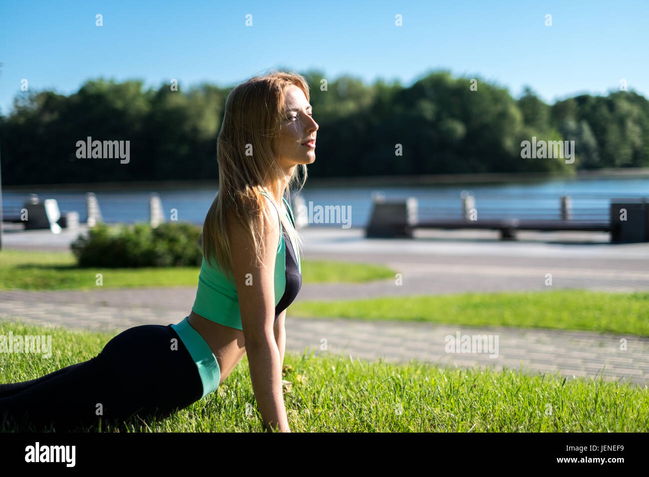 Woman lying on grass faisant un cobra yoga pose Banque D'Images