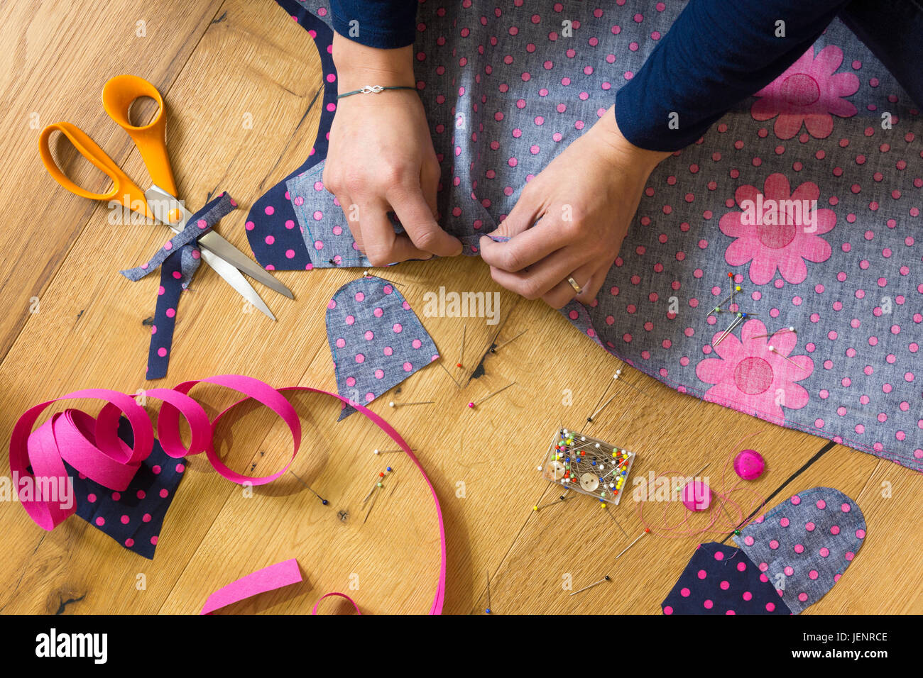 Une jeune femme épinglant un peu de tissu pour faire une robe. Thème : passe-temps, loisirs, arts et artisanat, création, couture, broderie Banque D'Images