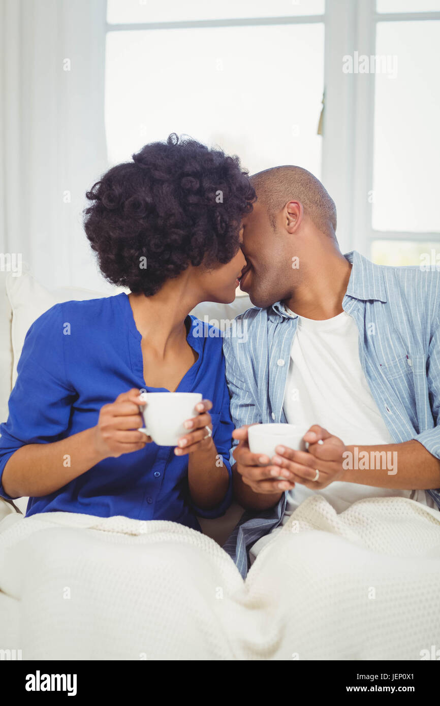 Couple heureux, baiser sur la canapé Banque D'Images