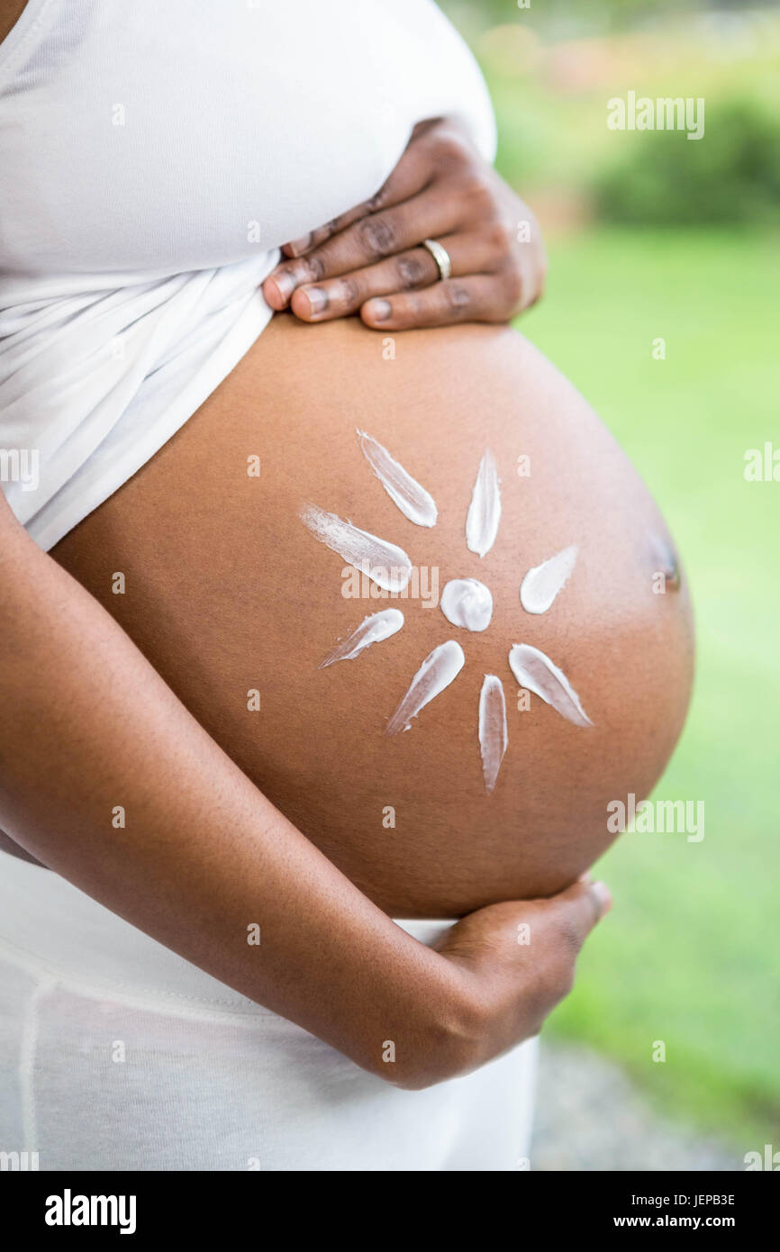 Femme enceinte l'application de la crème sur son ventre Banque D'Images