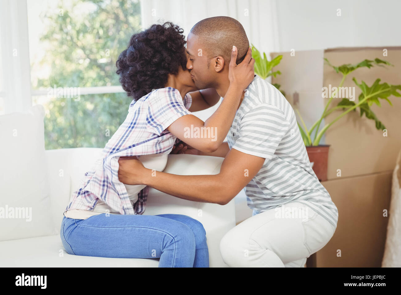 Couple heureux, baiser sur la canapé Banque D'Images
