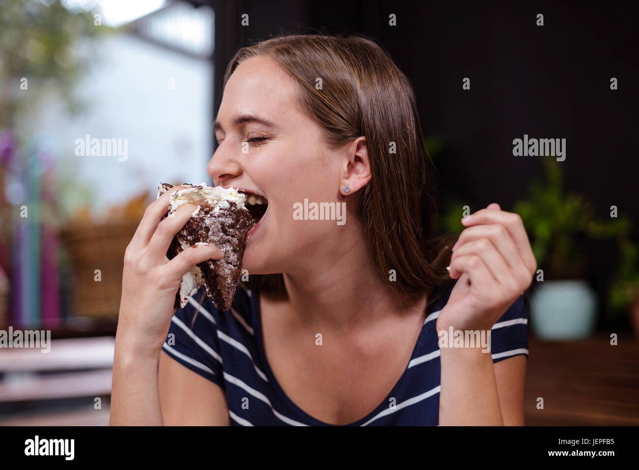 Jolie femme de manger du gâteau avec la main Banque D'Images