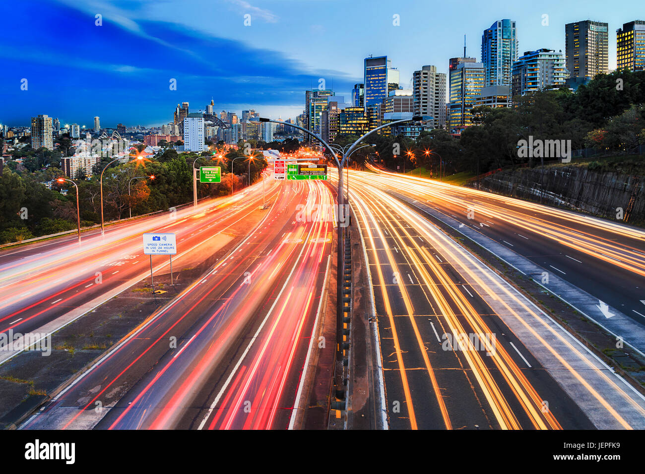 Large lit multi lane warringah freeway en passant par North Sydney au coucher du soleil avec des troubles de la conduite des voitures à partir de lignes de lumières rouge jaune. Banque D'Images