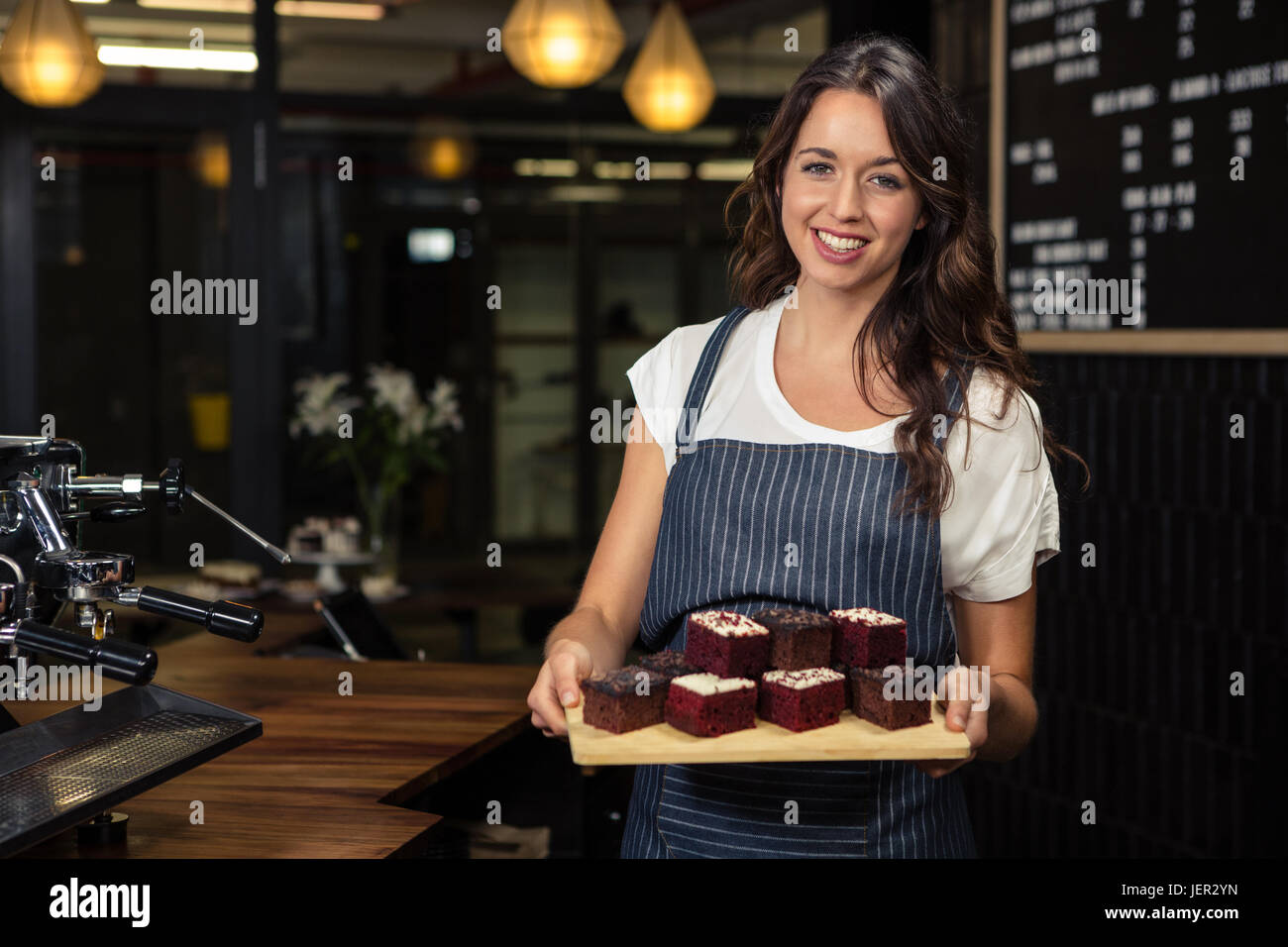 Smiling barista maintenant la plaque de gâteaux Banque D'Images