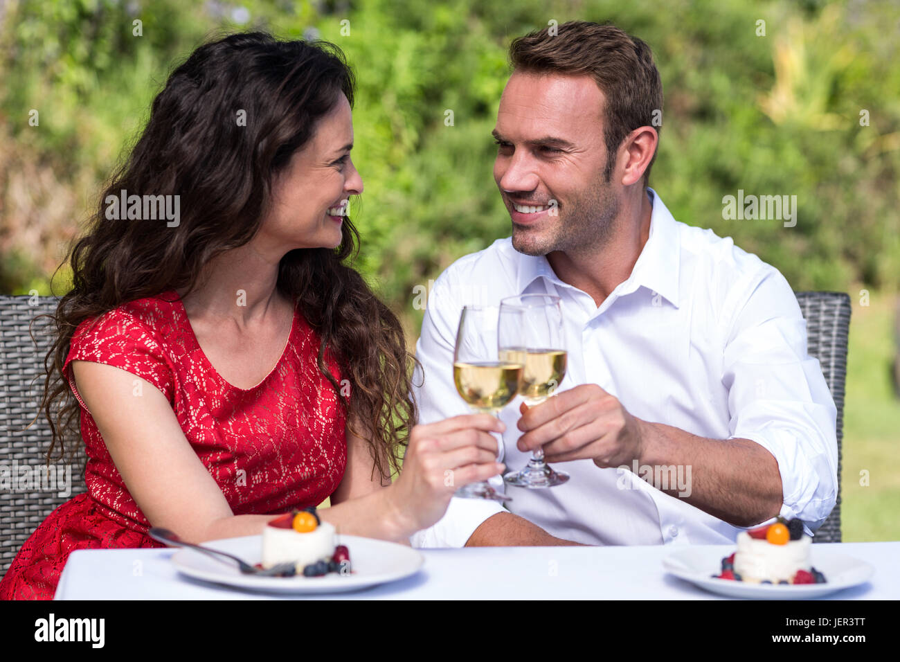 Happy young couple toasting with wine in lawn Banque D'Images