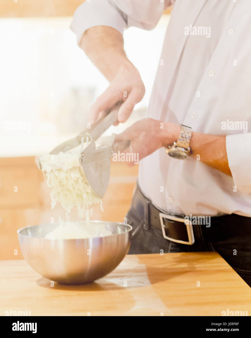 En appuyant sur l'homme par l'intermédiaire de presse-purée de pommes de terre Pommes de terre Banque D'Images