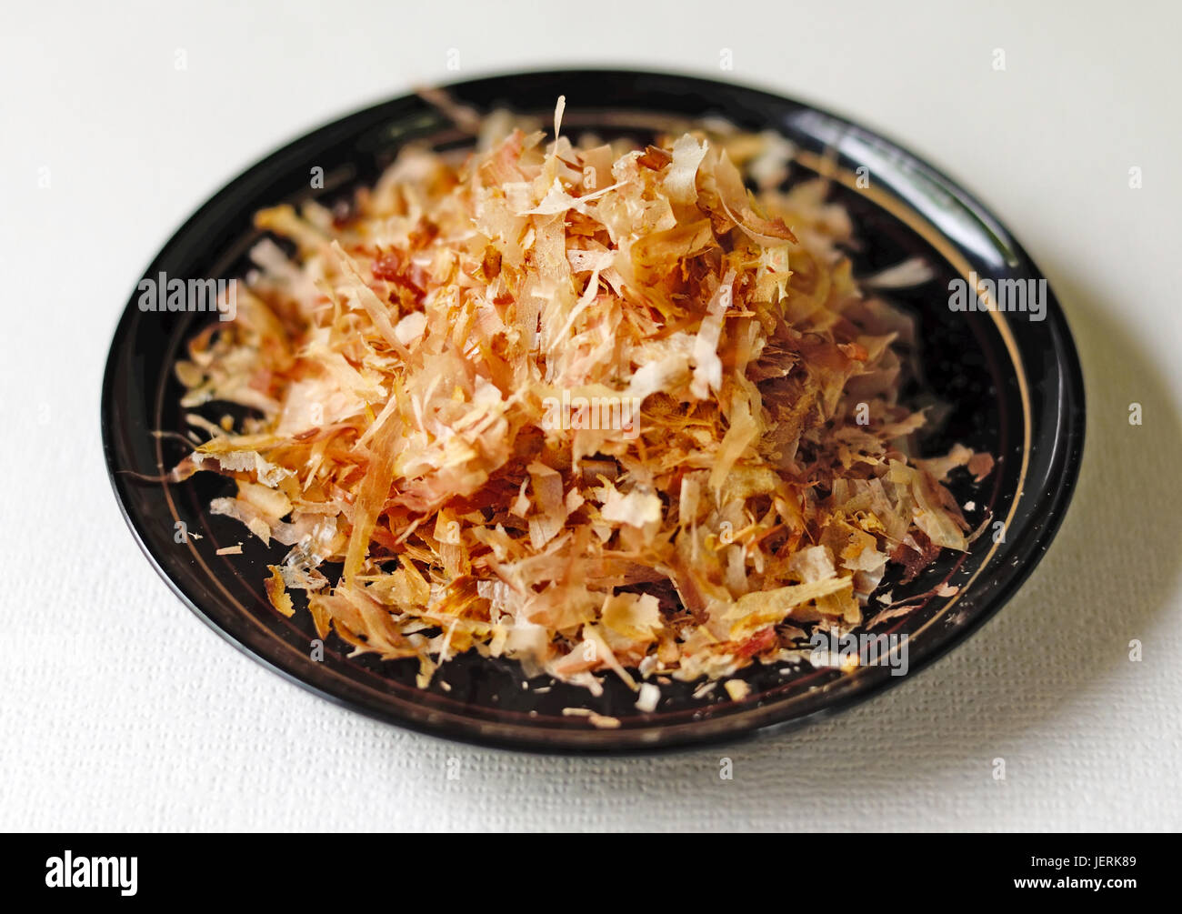 Gros plan du katsuo bushi (bonito flakes) sur un bol noir sur un fond blanc. Banque D'Images