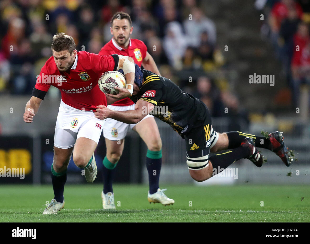 Les Lions britanniques et irlandais' Dan Biggar est abordé par les ouragans' Mark Abbott lors du tour match à la Westpac Stadium, Wellington. Banque D'Images