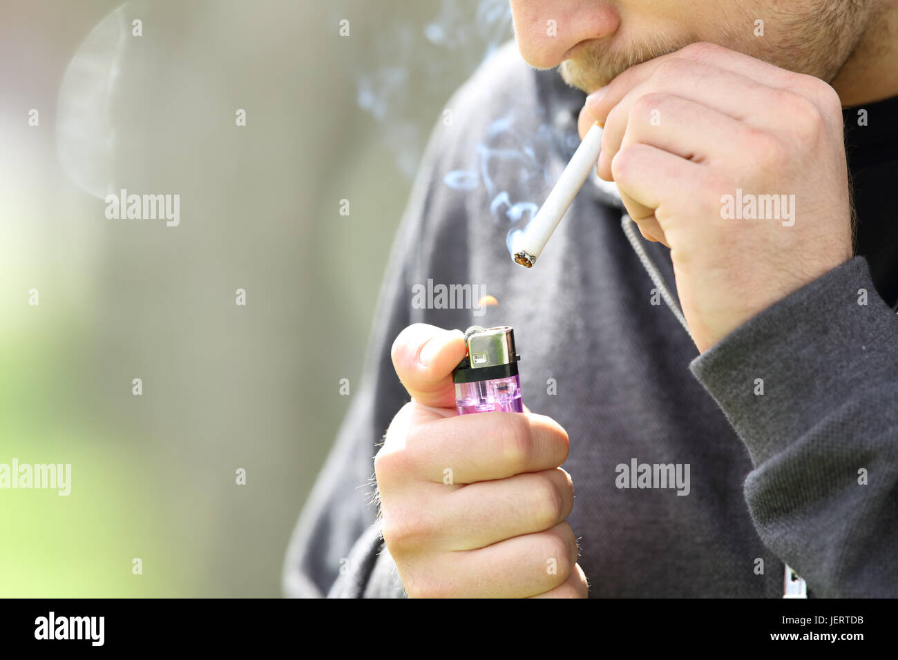 Close up of a teen mains tenant un briquet prêt à allumer une cigarette fumée secondaire Banque D'Images