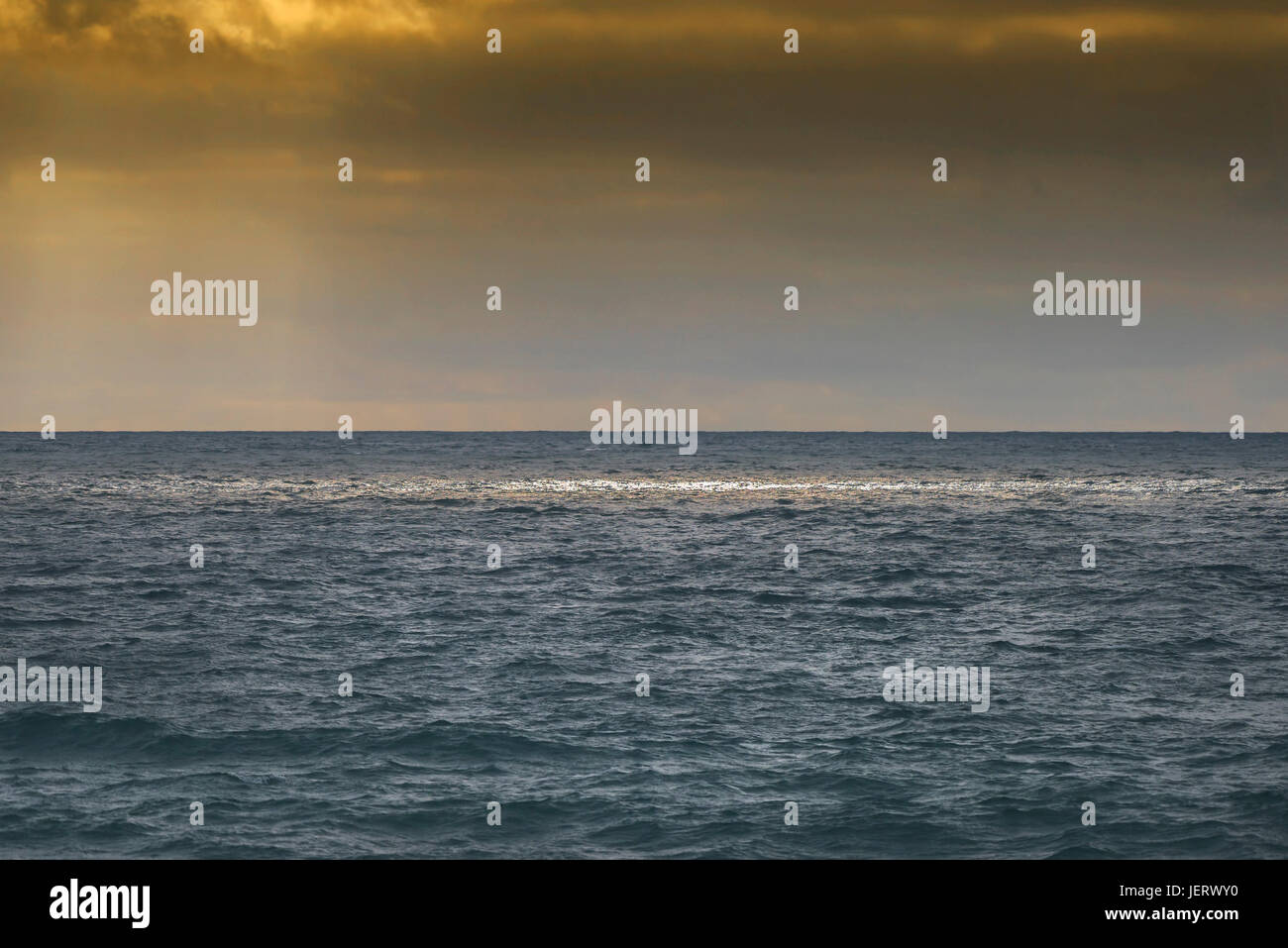 Soleil se brisant dans les nuages pour éclairer la mer. Banque D'Images