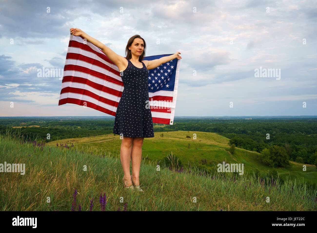 Fière femme avec un drapeau américain est debout au sommet d'une colline - le concept de l'indépendance jour USA Banque D'Images
