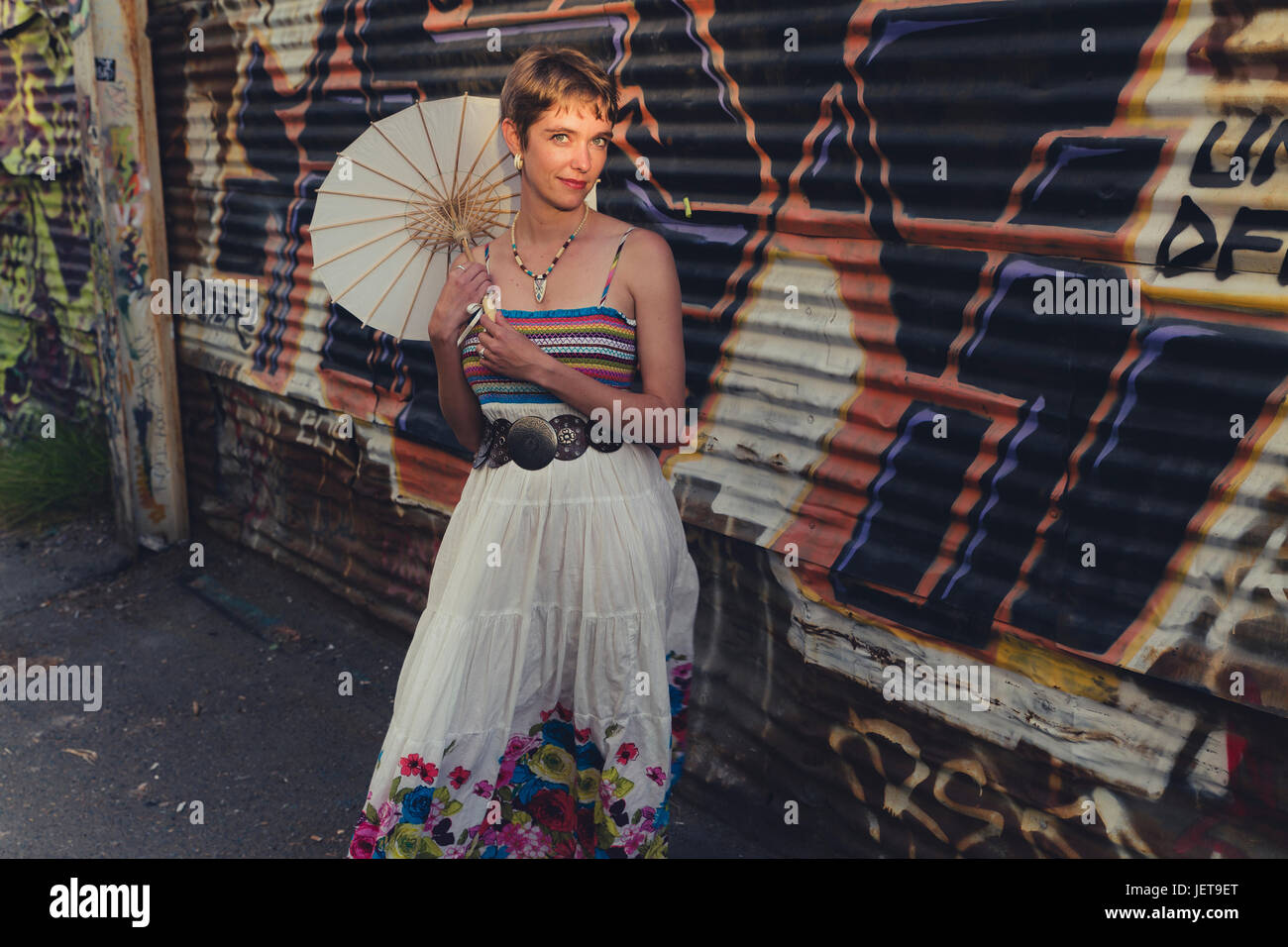 Une jeune femme de race blanche avec des caractéristiques androgynes porte des vêtements décontractés dans un milieu urbain Banque D'Images