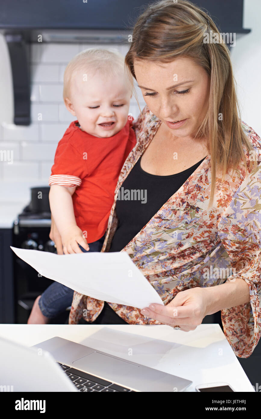 Mère occupée avec bébé face à journée stressante à la maison Banque D'Images