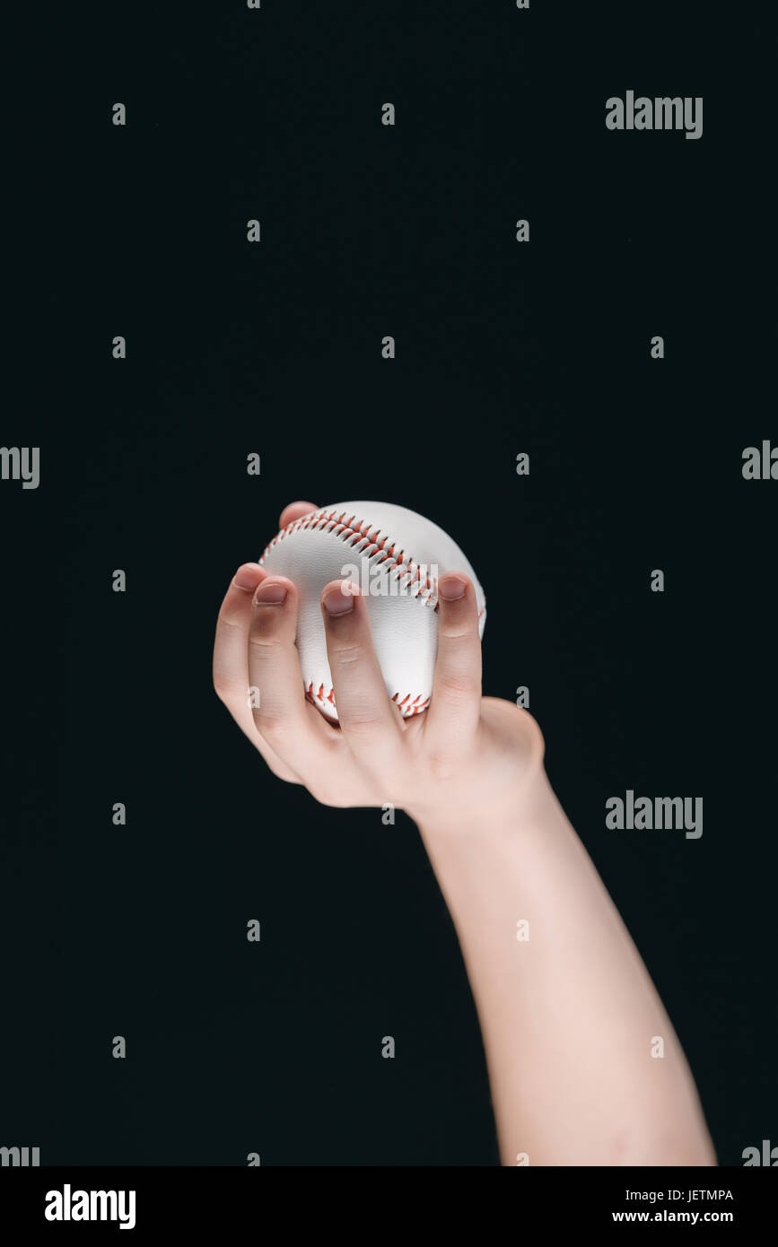 Vue partielle de kid holding baseball ball isolated on black Banque D'Images