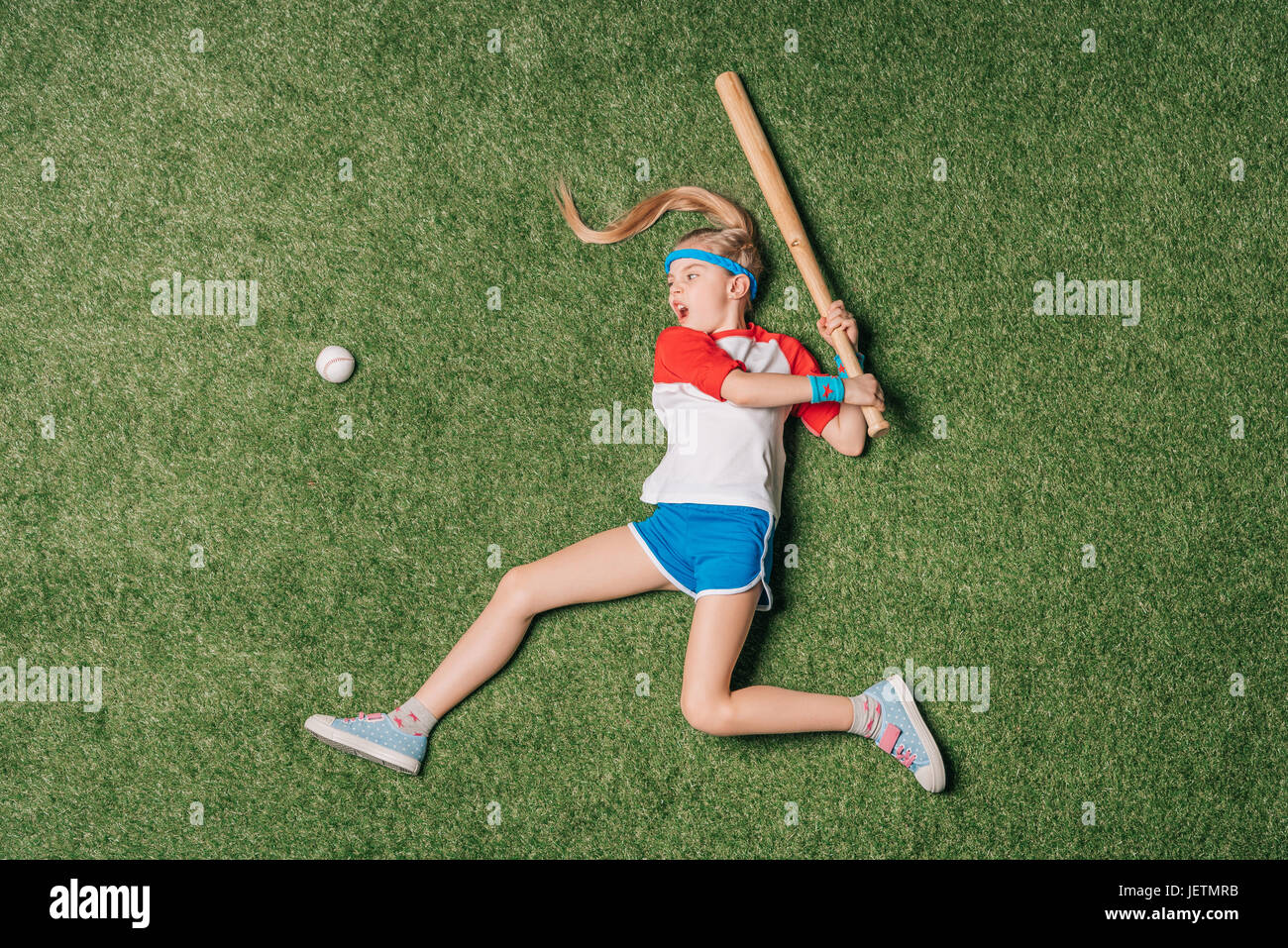 Vue de dessus de petite fille prétendant jouer au baseball sur l'herbe, l'athlétisme concept Banque D'Images