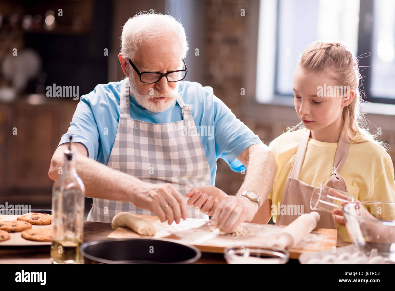 Petit-fils et son grand-père et la cuisson de la pâte pour faire des biscuits avec des ustensiles de cuisine à la table de cuisine, la cuisson au concept de cuisine Banque D'Images