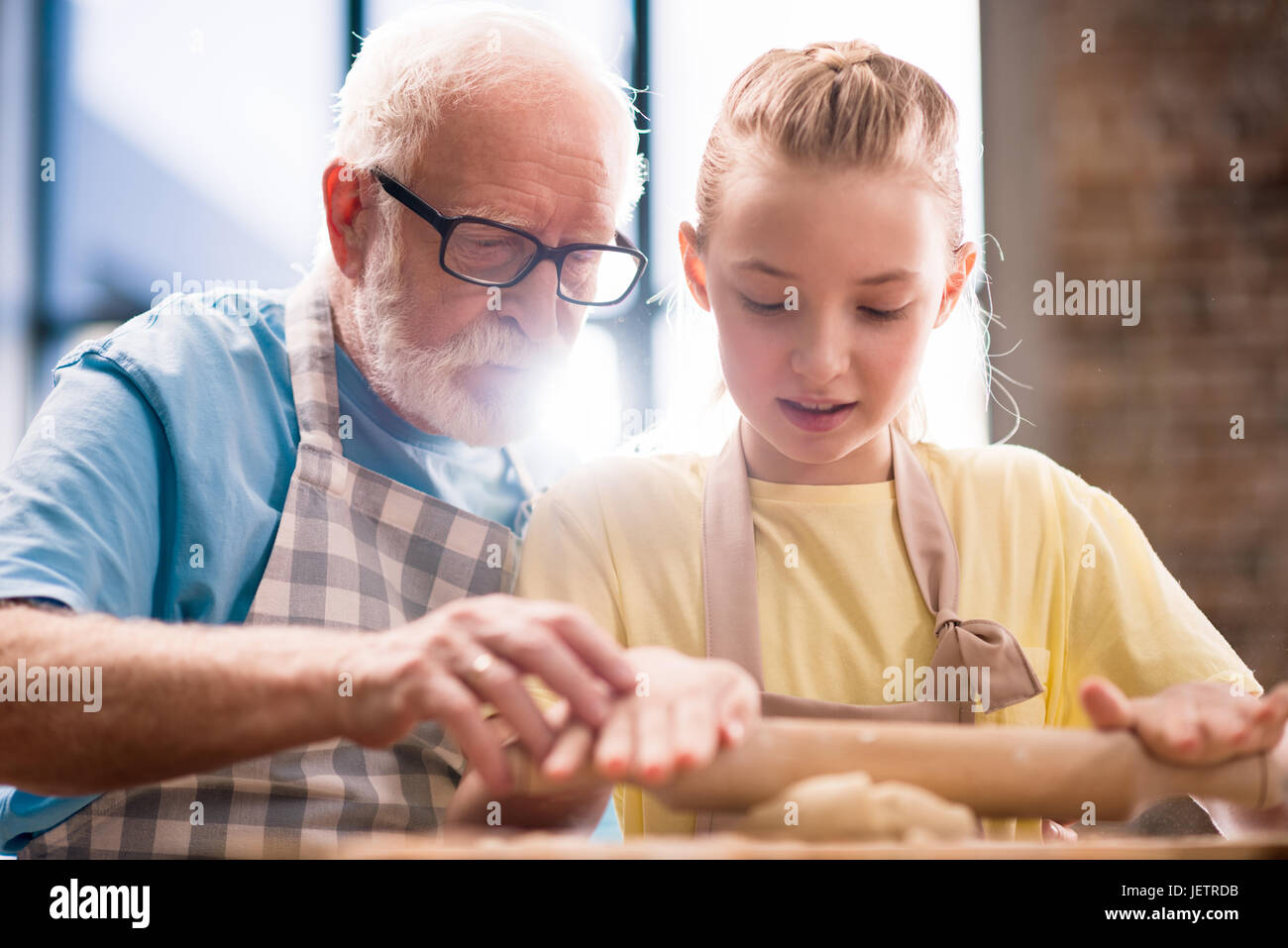 Petit-fils et son grand-père et la cuisson de la pâte pour faire des biscuits avec des ustensiles de cuisine à la table de cuisine, la cuisson au concept de cuisine Banque D'Images