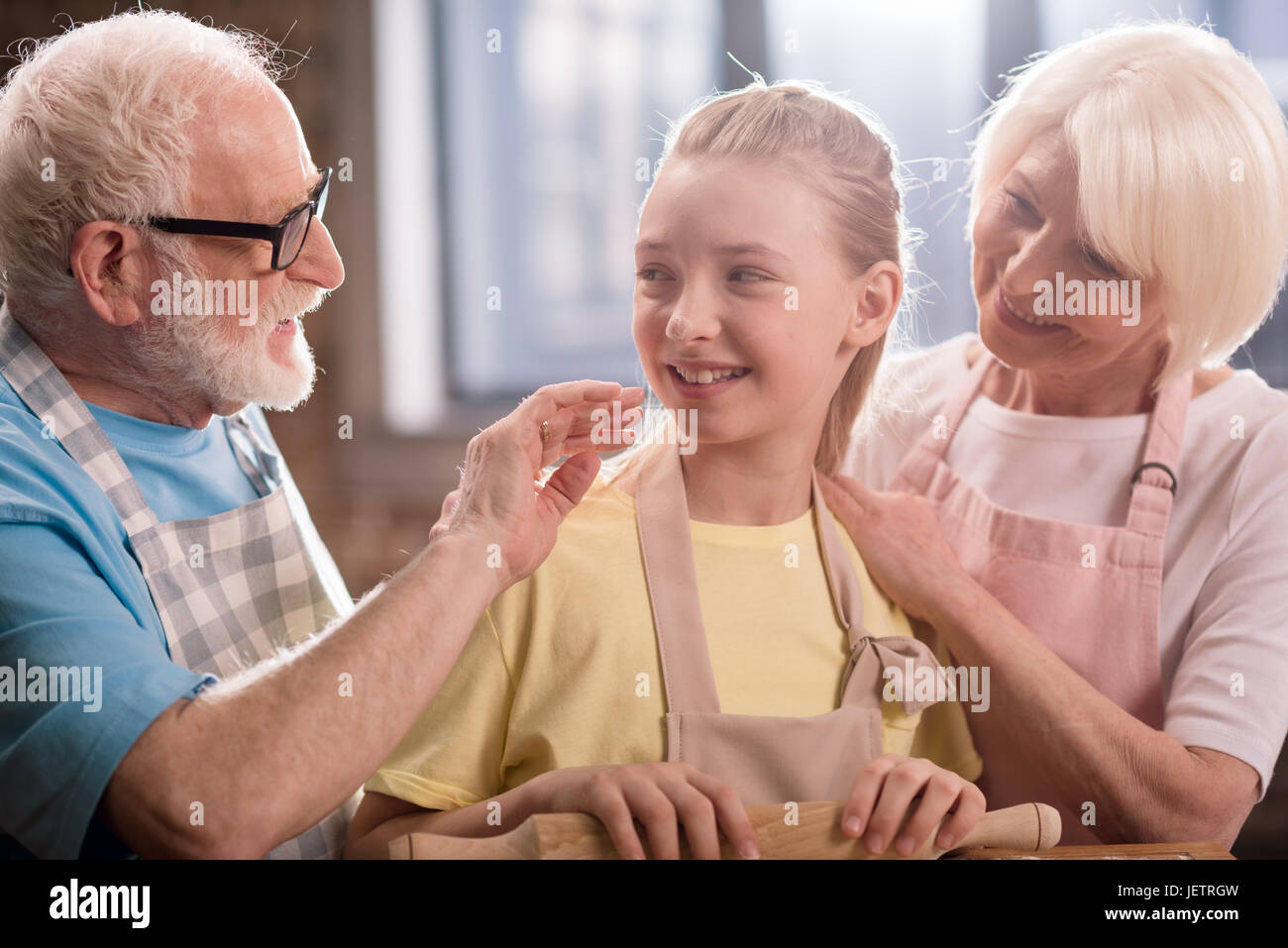 Grand-mère, grand-père et petite-fille de pétrissage et cuisson de la pâte pour les cookies avec des ustensiles de cuisine, la cuisson dans la cuisine concept Banque D'Images