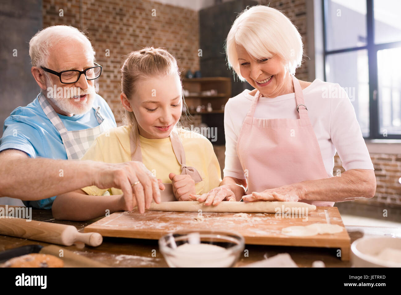 Grand-mère, grand-père et petite-fille de pétrissage et cuisson de la pâte pour les cookies à table de cuisine, la cuisson au concept de cuisine Banque D'Images