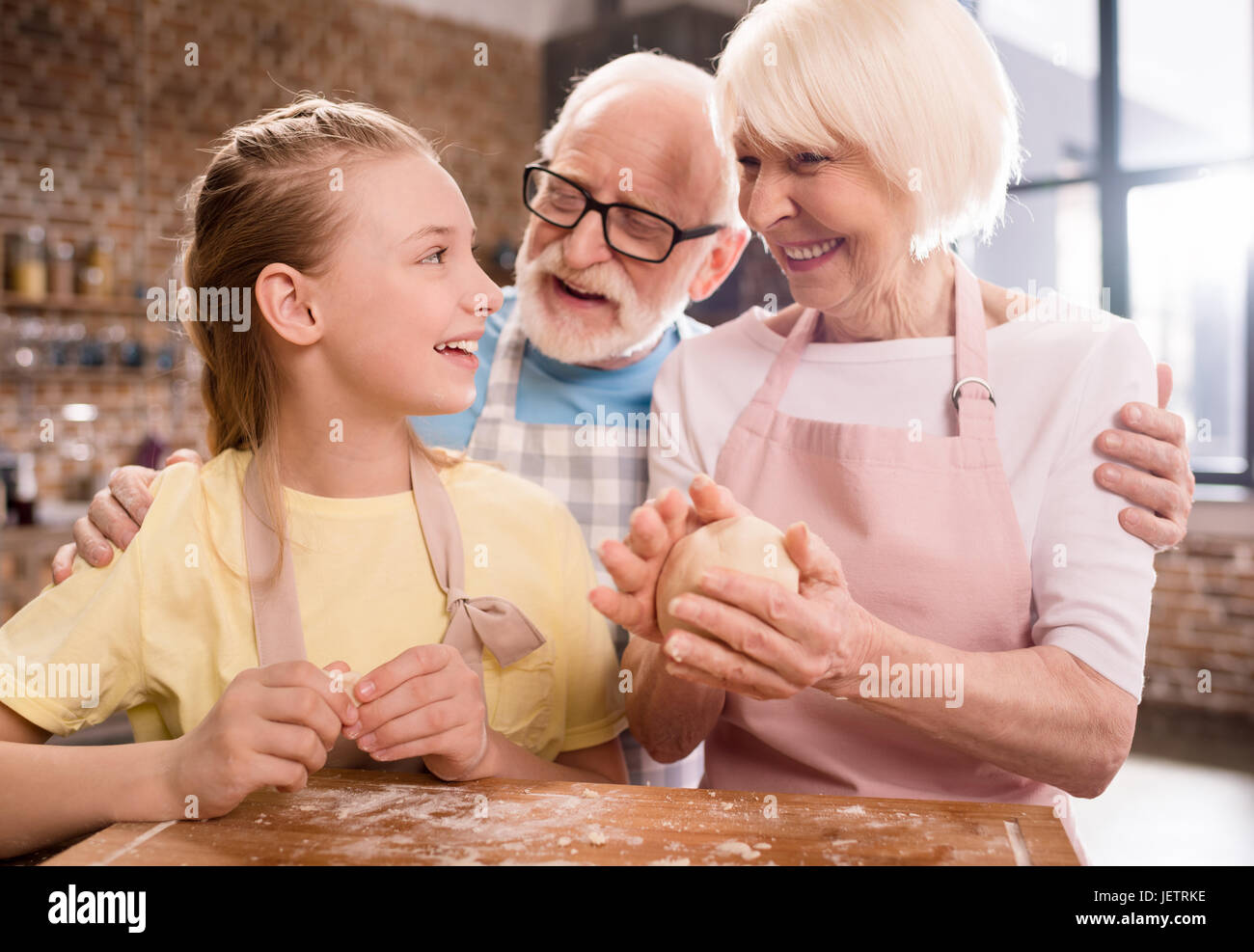 Grand-mère, grand-père et petite-fille de pétrissage et cuisson de la pâte pour les cookies à table de cuisine, la cuisson au concept de cuisine Banque D'Images