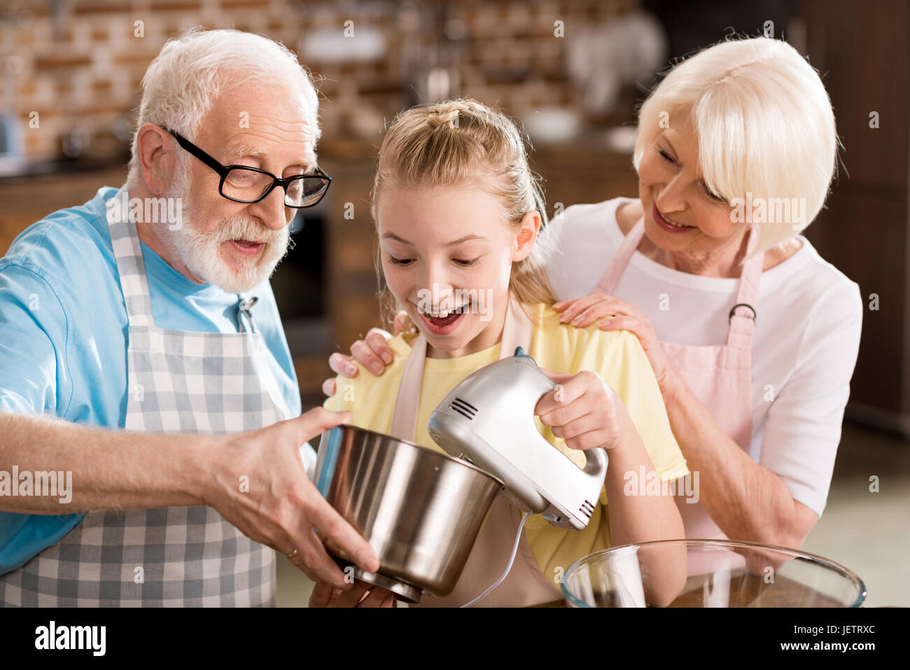 Senior woman looking at heureux grand-père et petite-fille de mélanger la pâte à gâteau Banque D'Images