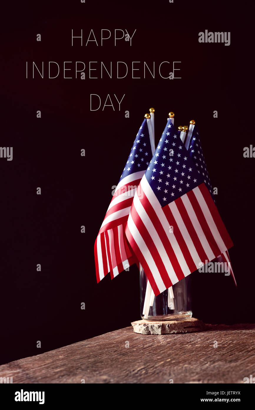 Certains des drapeaux américains dans un bocal en verre, sur une surface en bois rustique et le texte happy happy independence day sur fond noir Banque D'Images