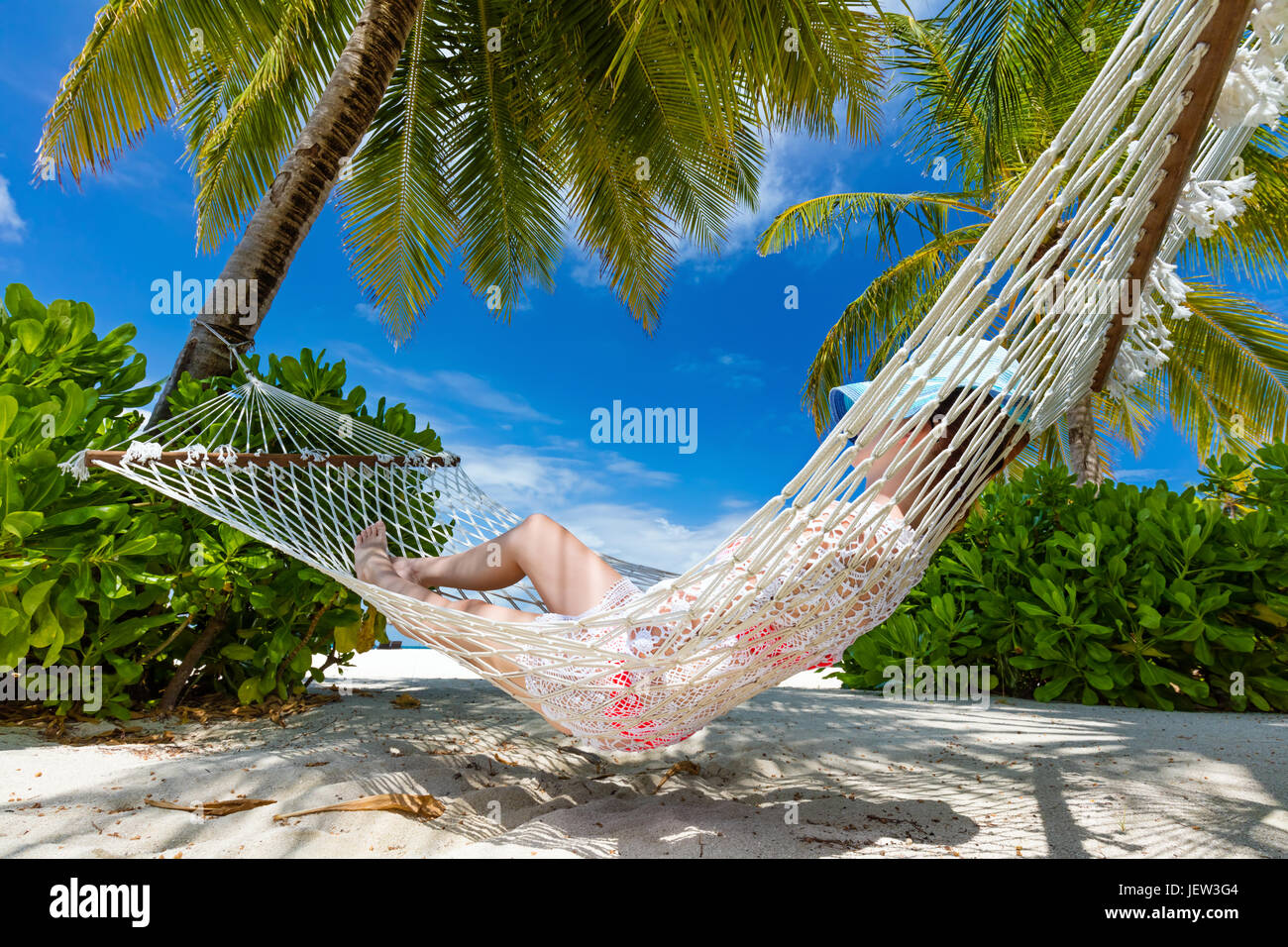 Woman swinging sur hamac entre les palmiers sur une plage tropicale. Maldives Banque D'Images