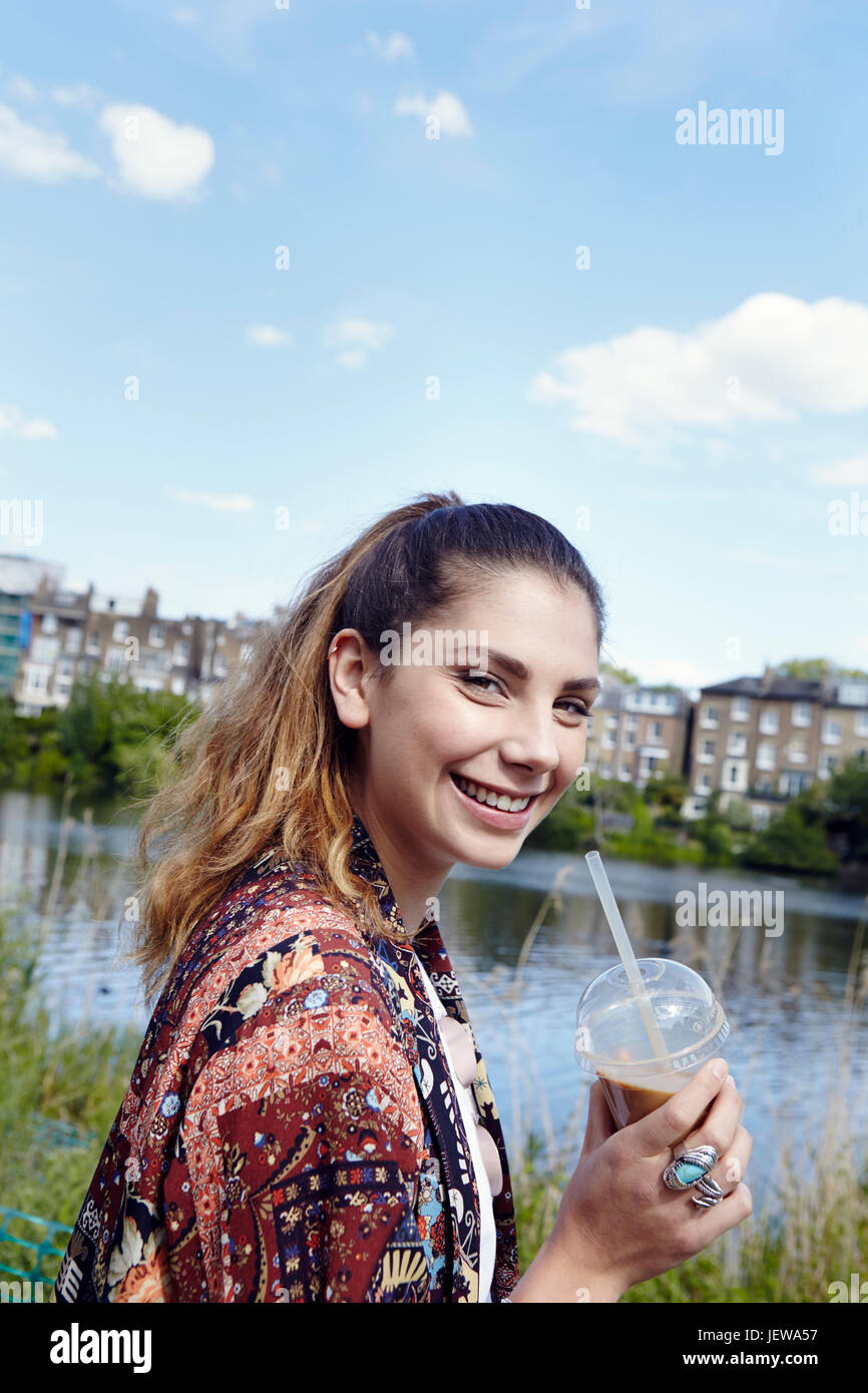 Portrait of smiling young woman holding drink Banque D'Images