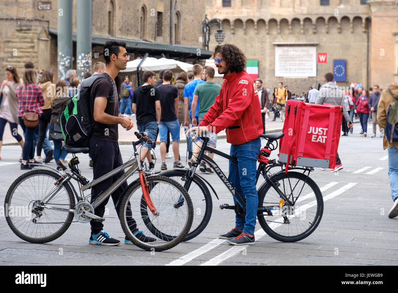 Bologne, Italie, 1 mai 2017 - Un vélo manger juste livrer courier parler avec un autre cycliste dans la place principale de Bologne Banque D'Images