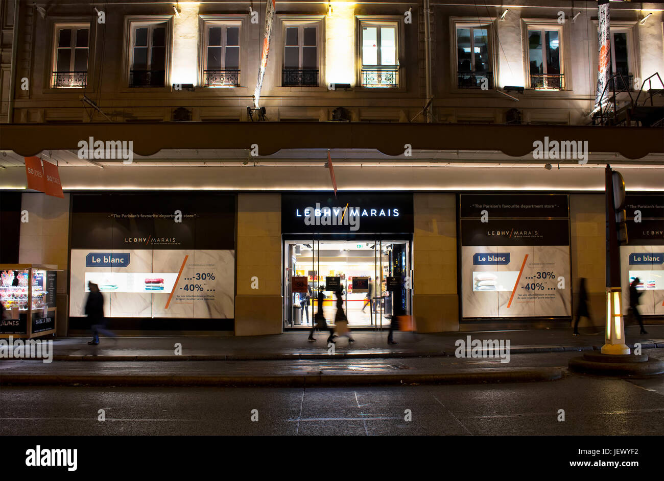 Voir des gens marcher dans motion floue en face d'un célèbre magasin de nuit dans le quartier du Marais de Paris. Le consumérisme et la période des ventes de con Banque D'Images