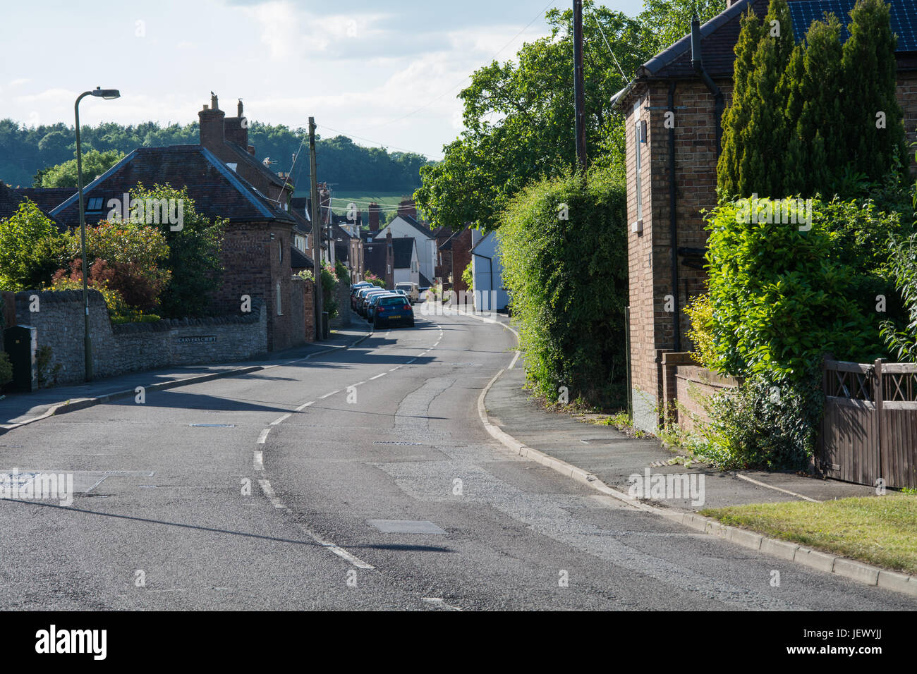 Une courbe sur la route d'une journée ensoleillée dans les régions rurales de l'Angleterre. Barrow Street, Much Wenlock, Shropshire, au Royaume-Uni. Banque D'Images