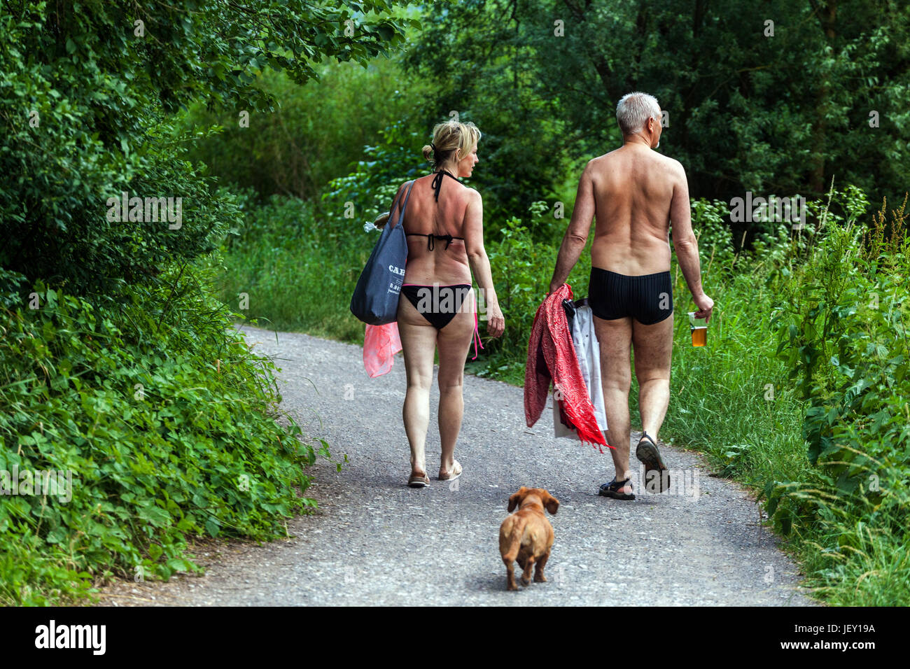 Vieillissement actif couple senior chien marchant sur la route de la rivière, des vacances d'été dans la vallée de la rivière Berounka, République tchèque vie quotidienne homme senior femme Banque D'Images