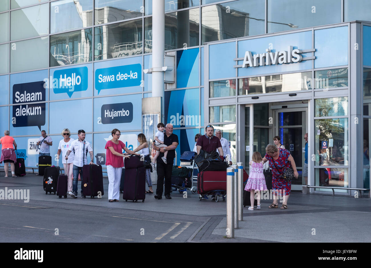 Les passagers avec bagages à l'extérieur de la porte pour le Hall des arrivées de l'aéroport de Birmingham, England, UK. Banque D'Images